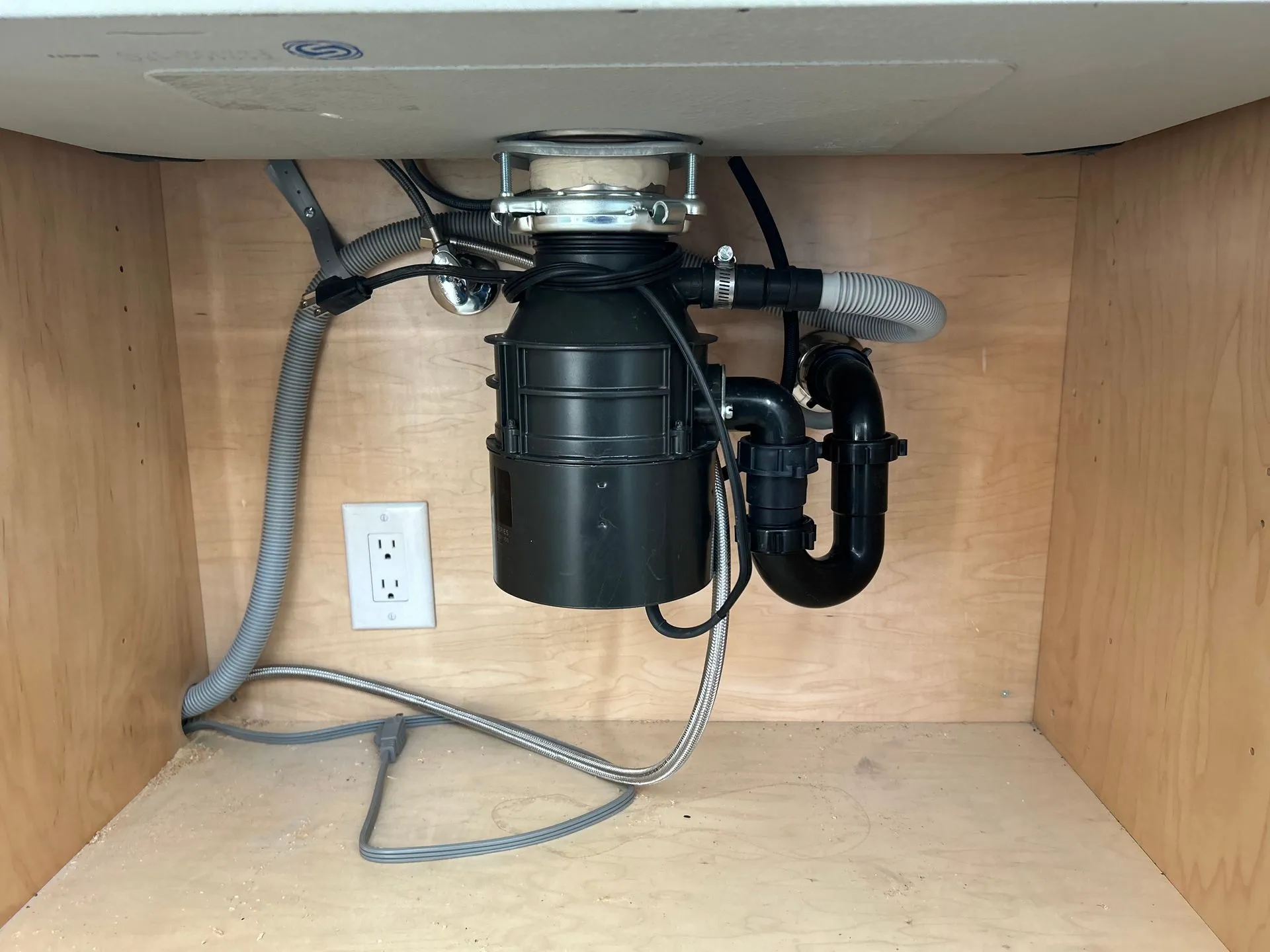 Garbage disposal and drain lines installed under a kitchen sink by KCM Mechanical