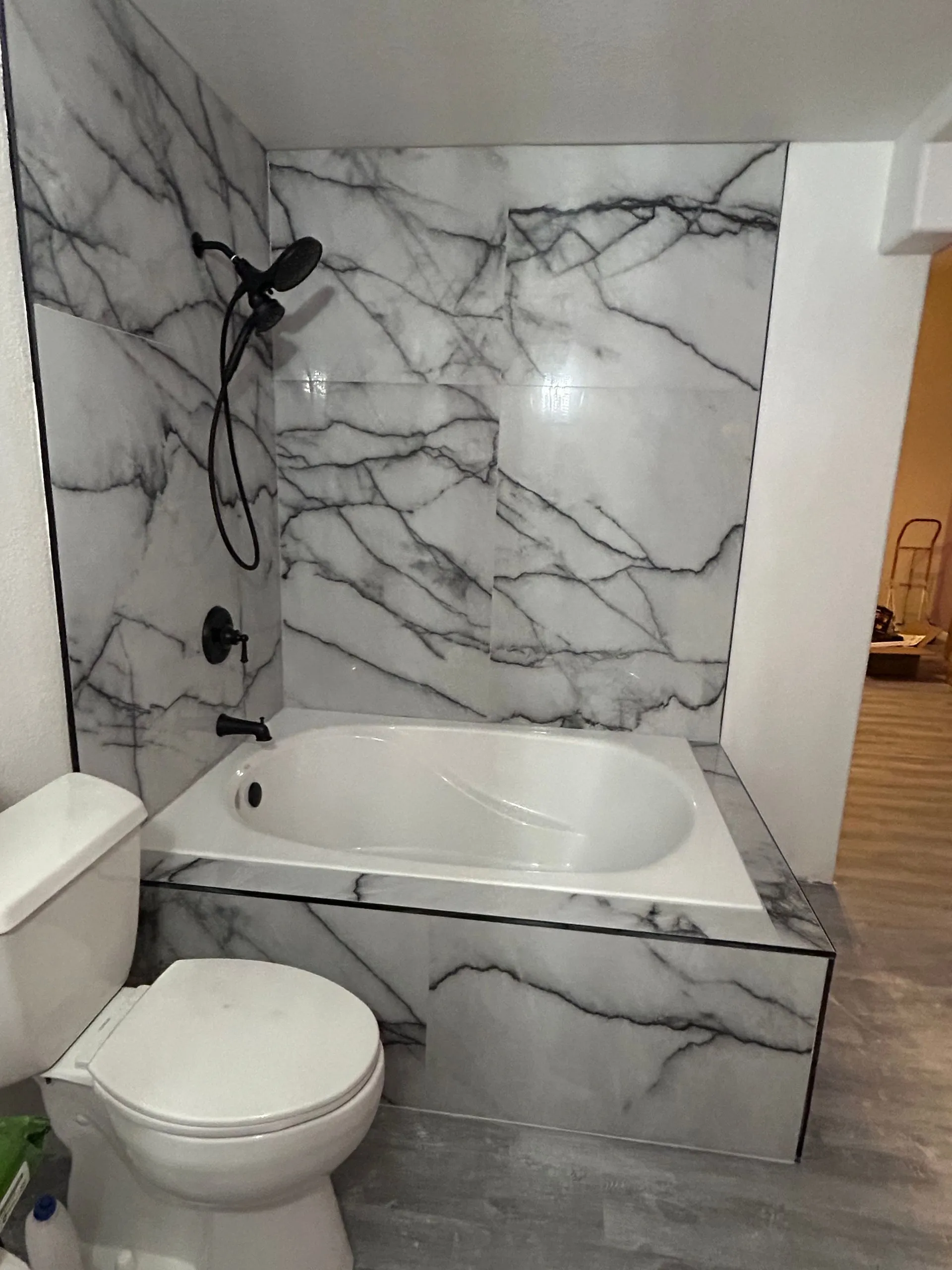 Bathtub with marble tile surround and matte black fixtures plumbed by KCM Mechanical